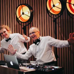 Dwóch DJ-ów w białych koszulach i czarnych muszkach, gotowych do zabawy. Zastanawiasz się, ile kosztuje orkiestra na wesele?