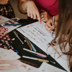 Goście piszą życzenia na kartkach, a obok leży aparat instax na weselu.