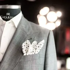 Elegancka szara marynarka w kratę z białą koszulą i wzorzystą poszetką. Detale tworzą stylową całość, podkreślając klasę.