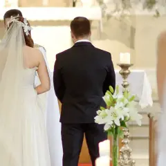 Para młoda podczas ceremonii ślubnej. W kościele panuje uroczysta atmosfera, a **limit osób na weselu** jest widoczny – obecni są tylko najbliżsi.