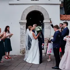 Para młoda całuje się przed kościołem, goście sypią bańki. To piękny ślub kościelny jednostronny.
