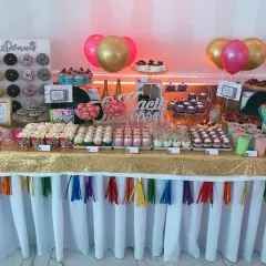 Słodki stół z donutami, babeczkami i deserami w słoiczkach, jak na wesele lata 80. Złoty obrus i kolorowe balony dodają blasku.