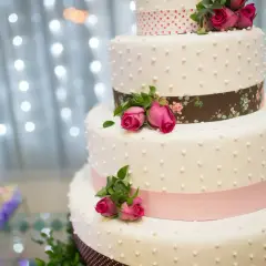 Elegancki tort weselny z różowymi różami i wstążkami. Idealny na uroczystość, jak piosenka do tortu weselnego.