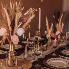Eleganckie wiejskie wesele dekoracje stołu: bukiety z traw, róże, świece i złote naczynia tworzą ciepłą atmosferę.