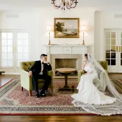 Para w eleganckich strojach siedzi naprzeciwko siebie, rozmawiając o tym, jak wziąć ślub cywilny.