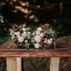 Dwa bukiety ślubne boho z różami, jeżynami i gałązkami na drewnianym stole.