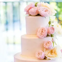 Elegancki tort weselny glamour ozdobiony delikatnymi różami w odcieniach pudrowego różu i kremu.