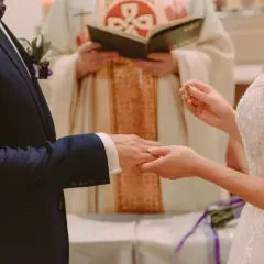 Para ślubna wymienia obrączki. Czy sakrament bierzmowania jest potrzebny do ślubu? Kapłan błogosławi parę.