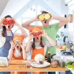 Rodzina przygotowuje kolację zapoznawczą rodziców, żartując z warzywami. Mama i tata zasłaniają oczy pomidorami i kapustą, a dzieci robią to samo z ogórkami i pomidorkami.