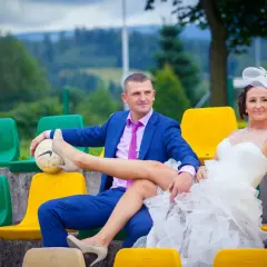 Para wykupiny panny młodej siedzi na trybunach. Pan młody trzyma piłkę, na której opiera nogę panny młodej.