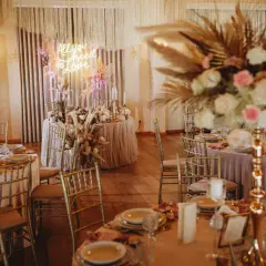 Elegancka sala weselna z neonem "All you need is love". Złote krzesła i pastelowe dekoracje. Zastanawiasz się, ile bierze dekoratorka na wesele?