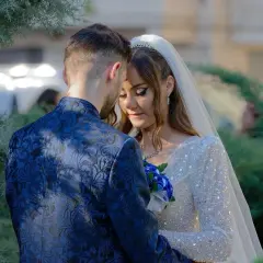 Para młoda w objęciach, panna młoda w sukni z cekinami i welonie, pan młody w granatowym garniturze.