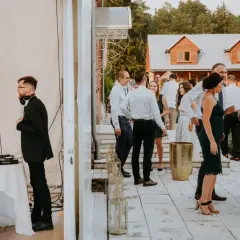 DJ przygotowuje się do przyjęcia weselnego w lesie. Goście bawią się na tarasie przed domem.
