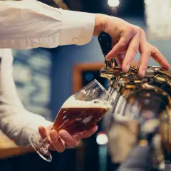 Barman nalewa piwo do kieliszka. Zastanawiasz się, ile piwa na wesele? Oto odpowiedź!
