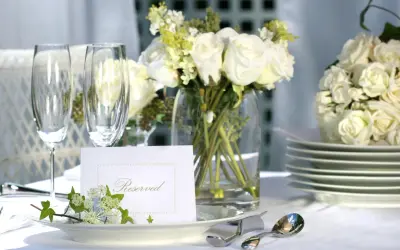 Elegancko nakryty stół z białymi różami, kieliszkami i kartą "Reserved". Idealny na przyjęcie, gdzie wedding planner cena jest kluczowa.