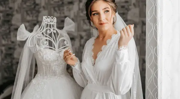 Panna młoda w białej szacie, obok sukni ślubnej na manekinie. Czyżby ślub w maju przesądy nie były jej straszne?