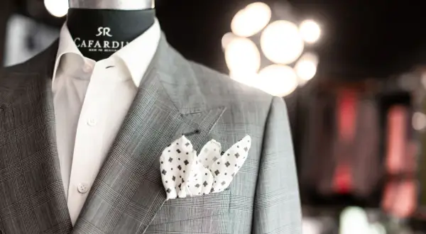 Elegancka szara marynarka w kratę z białą koszulą i wzorzystą poszetką. Detale tworzą stylową całość, podkreślając klasę.