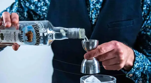 Barman nalewa Żubrówkę do kieliszka z lodem. Idealny wybór na wesele, jeśli szukasz czegoś mocniejszego niż wina na wesele ranking.