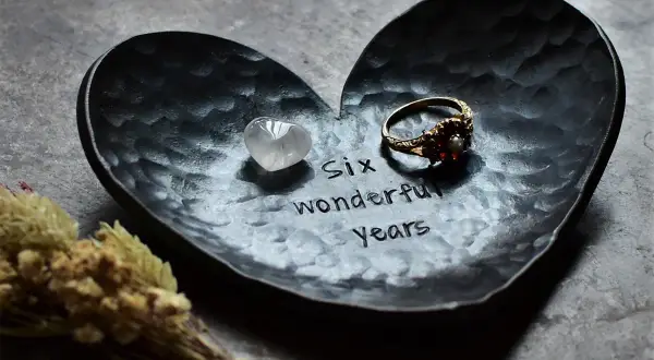 Czarna, sercowata tacka z wygrawerowanym napisem "Six wonderful years", pierścionkiem i kamieniem.