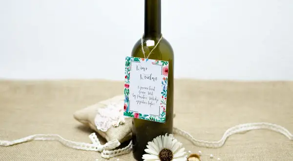Butelka wina z etykietą "Wino Weselne" i ozdobami. Może to być prezent, który zawiera śmieszne wierszyki na wesele za flaszkę.