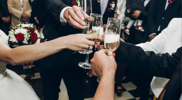 Wznoszenie toastu szampanem na weselu. Radość i celebracja, a także odpowiedź na pytanie: ile napoi na wesele?