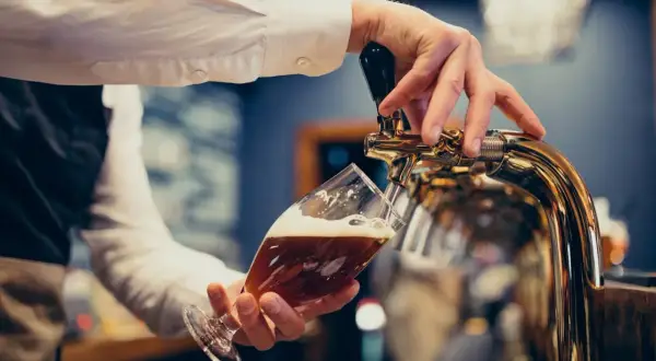Barman nalewa piwo do kieliszka. Zastanawiasz się, ile piwa na wesele? Oto odpowiedź!