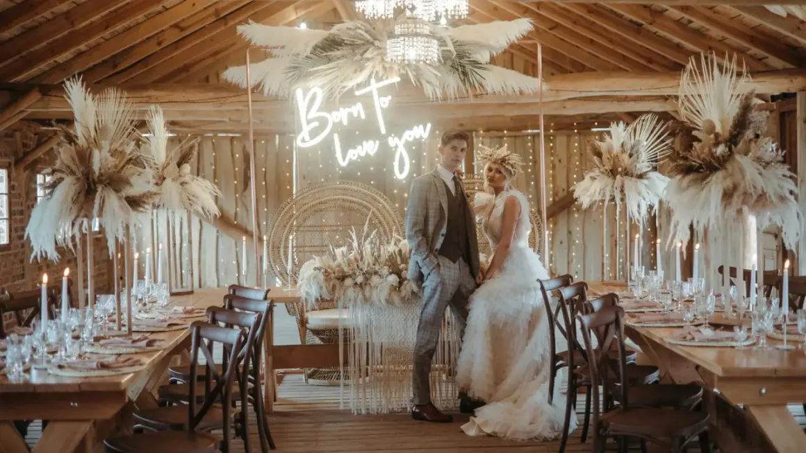 Eleganckie wesele w stodole: boho dekoracje z traw pampasowych, neon "Born to love you" i para młoda.