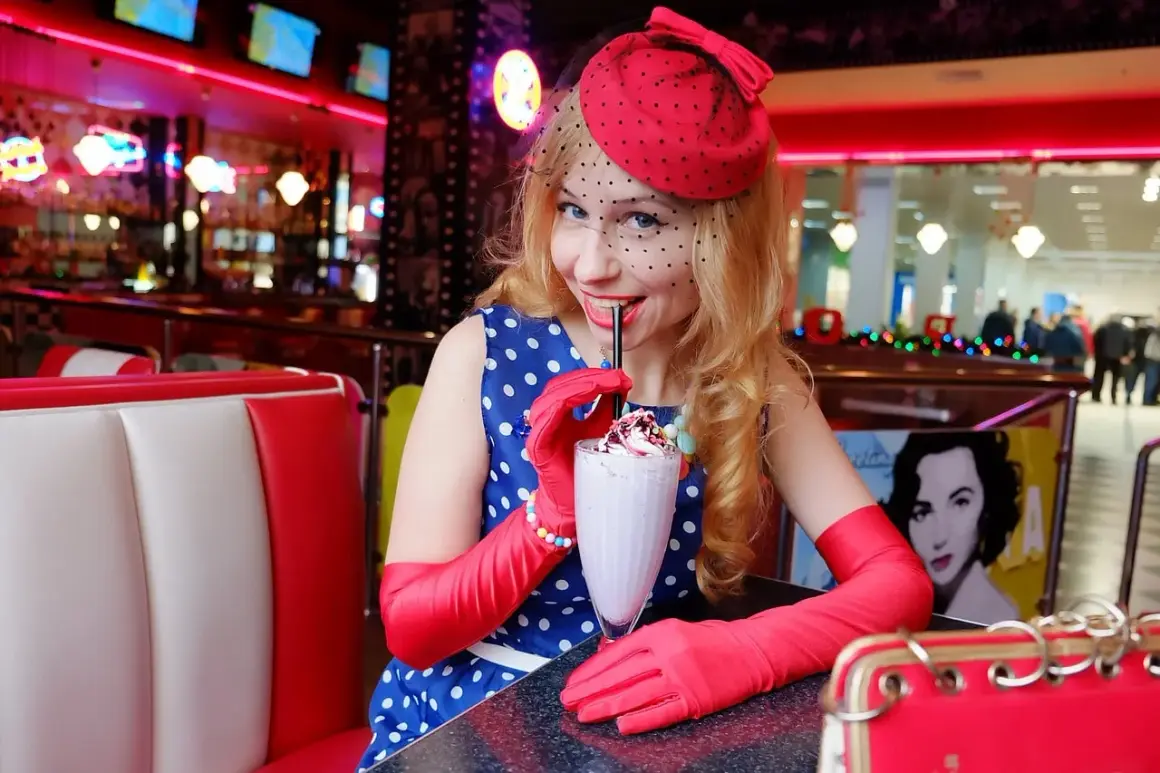 Kobieta w stylu pin up pije mleczny koktajl w retro restauracji.
