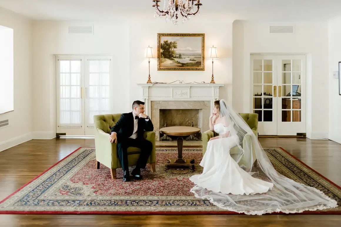 Para w eleganckich strojach siedzi naprzeciwko siebie, rozmawiając o tym, jak wziąć ślub cywilny.