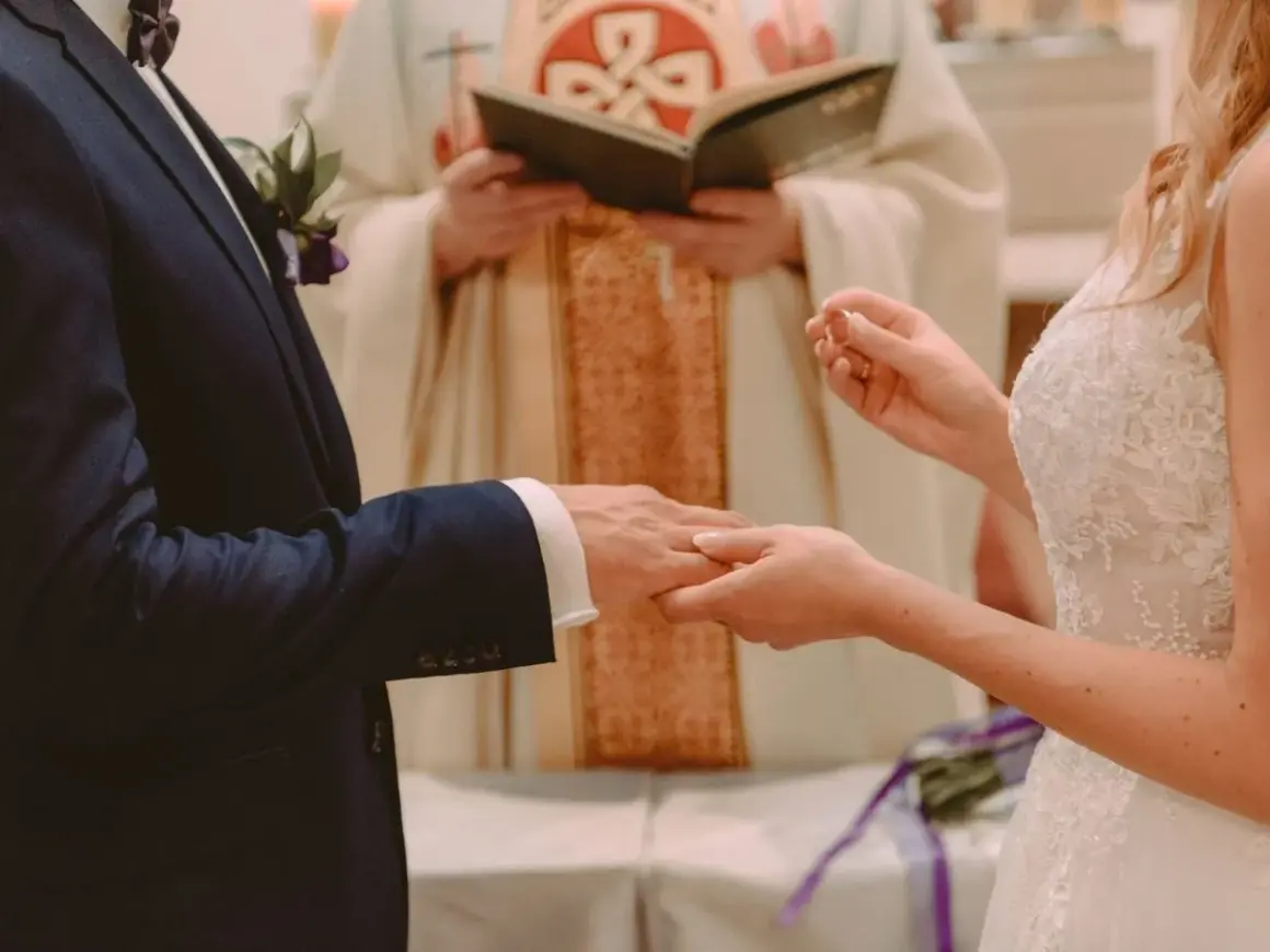 Para ślubna wymienia obrączki. Czy sakrament bierzmowania jest potrzebny do ślubu? Kapłan błogosławi parę.