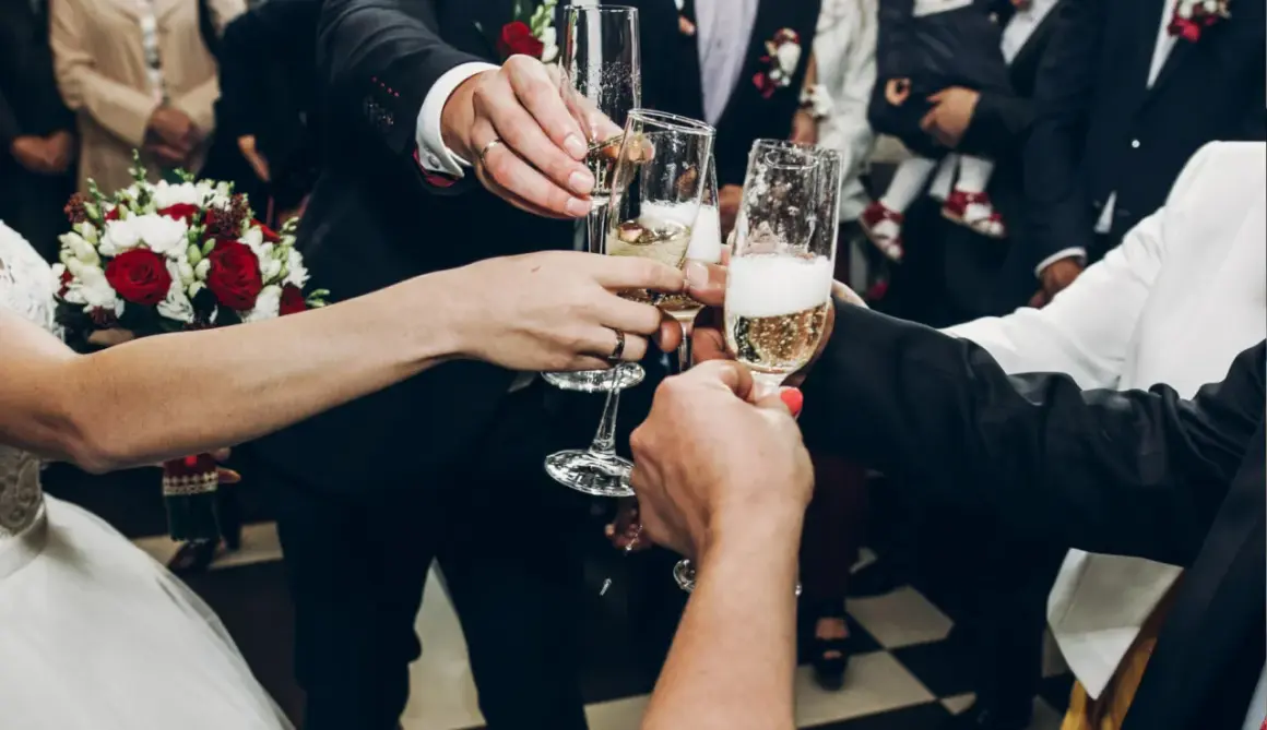 Wznoszenie toastu szampanem na weselu. Radość i celebracja, a także odpowiedź na pytanie: ile napoi na wesele?