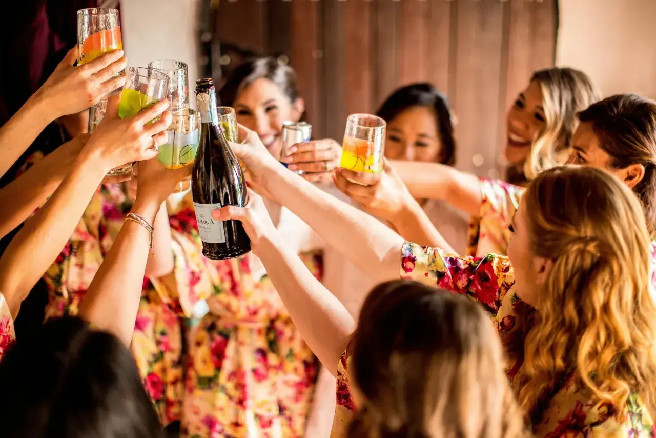 Radosne kobiety w szlafrokach wznoszą toasty z kolorowymi drinkami i butelką prosecco. Idealna organizacja wieczoru panieńskiego pełna śmiechu i celebrowania.