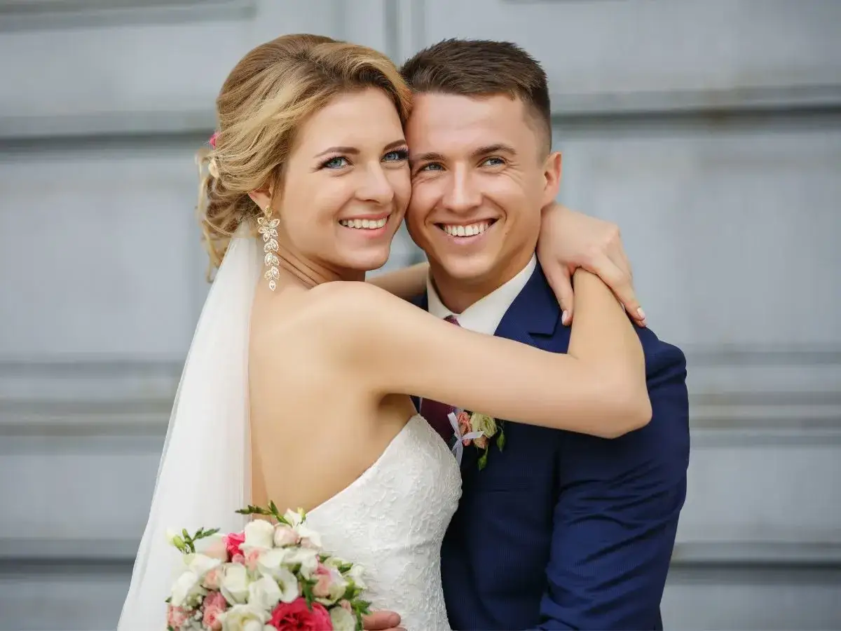 Szczęśliwa para młoda, panna młoda w białej sukni i pan młody w granatowym garniturze, świętują ślub syna. Urlop okolicznościowy udany!