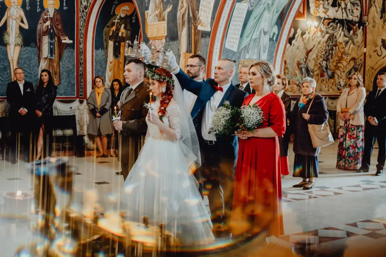 Para młoda podczas ceremonii ślubu kościelnego jednostronnego. Panna młoda w białej sukni, pan młody w garniturze.