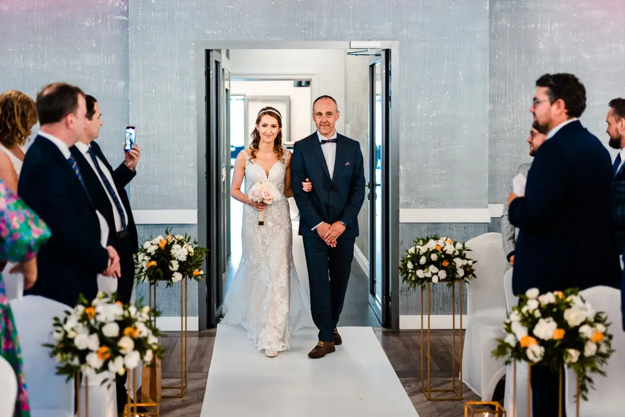 Panna młoda z ojcem idzie do ołtarza. Czy rodzice mogą być świadkami na ślubie cywilnym? Tak, to piękna tradycja.