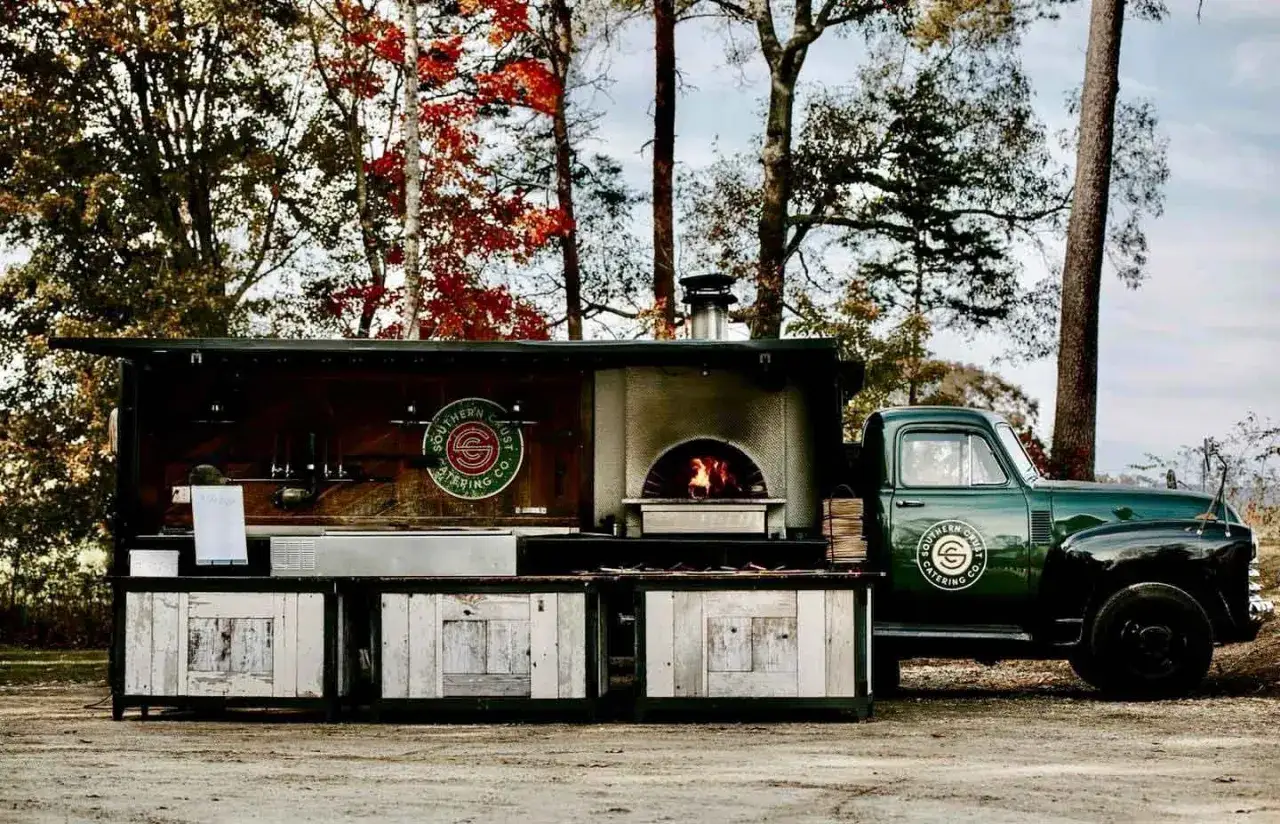 Mobilna piekarnia z piecem opalanym drewnem, gotowa na wyjątkową pizza na weselu.