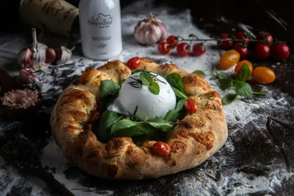 Wyjątkowa pizza na weselu z burratą, pomidorkami i ziołami. Idealna na uroczystość.