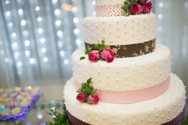 Elegancki tort weselny z różowymi różami i wstążkami. Idealny na uroczystość, jak piosenka do tortu weselnego.