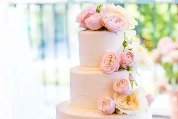 Elegancki tort weselny glamour ozdobiony delikatnymi różami w odcieniach pudrowego różu i kremu.