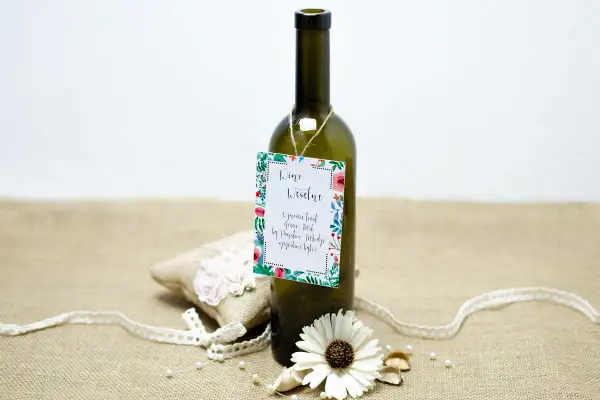 Butelka wina z etykietą "Wino Weselne" i ozdobami. Może to być prezent, który zawiera śmieszne wierszyki na wesele za flaszkę.
